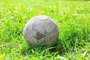 Old soccer ball on the green grass photo