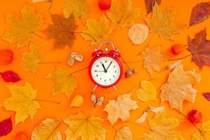 Autumn postcard with fall leaves and alarm clock