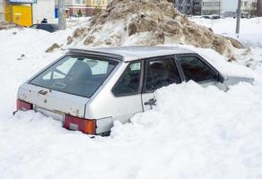 el coche se quedó atascado en la nieve. dejado para el invierno bajo la nieve foto