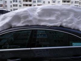 Street photo. Big snowdrifts in the city. Thick layer of snow on the car. photo