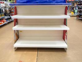 estantes vacíos en la tienda. Colocación de mercancías en un supermercado. foto