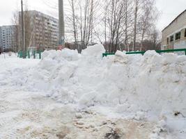 Street photo. Big snowdrifts in the city. The path after the passage of the snowplow. photo