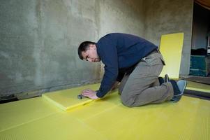 Installation of expanded polystyrene in the room for floor insulation, repair work alone, yellow expanded polystyrene. photo