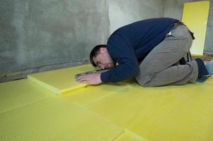 Installation of expanded polystyrene in the room for floor insulation, repair work alone, yellow expanded polystyrene. photo