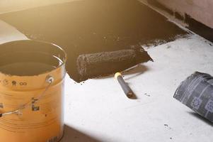 Applying hot resin to the floor for waterproofing, roller and bucket of resin. photo