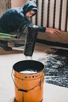 Applying hot resin to the floor for waterproofing, roller and bucket of resin. photo