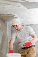 A man with a small spatula applies lime plaster on a large spatula, lime plaster on the walls and ceiling. photo