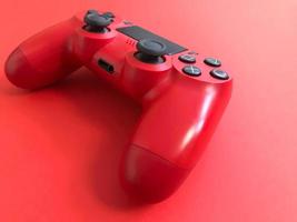 Beautiful red digital modern new game joystick for computer video games gamepad on a red background photo
