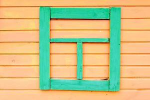 The texture of wooden planks of yellow with seams horizontal painted with natural paint and green falsh-window boarded with planks dummy. The background photo