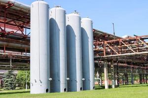 A large concrete technological industrial installation at a chemical petrochemical refinery with capacitive pipes by pumps compressors heat exchangers by pipelines and buildings photo