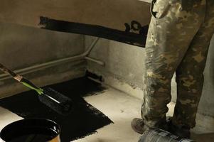 Waterproofing the floor in a private house, applying liquid resin to the floor, concrete screed and waterproofing. photo