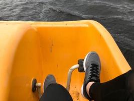 piernas en zapatillas deportivas grises botas de pedal en un catamarán amarillo foto