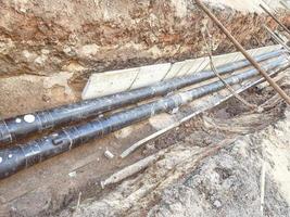 laying of underground communications for residential buildings. black plumbing pipes made of durable and reliable material lie on the foundation for digging into the ground photo