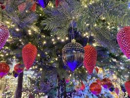 ramas verdes de un esponjoso árbol navideño festivo de año nuevo con juguetes en bolas y bombillas y guirnaldas brillantes, fondo foto