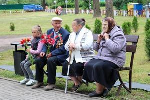 An old male grandfather is a veteran of World War II sitting on a bench with grandmothers and a flower. on the day of victory Moscow, Russia, 05.09.018 photo