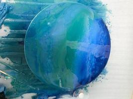 The process of creating a home-made trendy abstract modern pattern painted with a brush of acrylic blue multi-colored resin on a round wooden boar photo