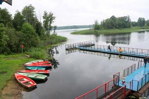 gente, hombres están pescando desde el pontón, delantal, puente en el lago con patos y botes en la orilla en el centro de recreación, sanatorio en otoño foto