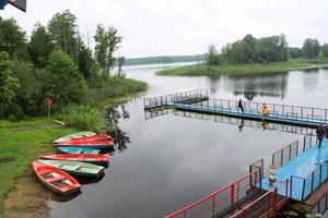 People, men are fishing from the pontoon, apron, bridge on the lake with ducks and boats on the shore at the recreation center, sanatorium in the fall photo