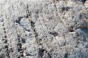 Texture of natural natural carved solid strong rough rough sharp textured mineral gray brown stone cobblestone on the walls of the rock. Stone background photo