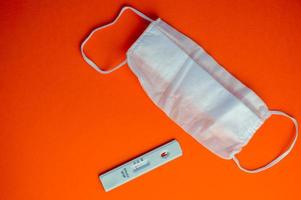 test for coronavirus on an orange background. on a matte background a sensitive strip for coronavirus, a mask. taking care of your health photo
