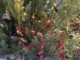 ramas verdes de un esponjoso árbol navideño festivo de año nuevo con juguetes en bolas y bombillas y guirnaldas brillantes, fondo foto