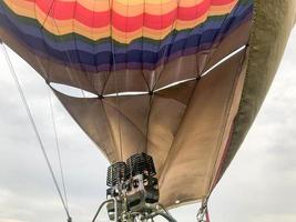 Large powerful metal iron burners, thermal hair dryers with a fire to heat hot air in a large multi-colored bright round rainbow colored striped flying balloon. The background photo