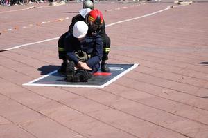 Men firefighter in fireproof suit and helmet saves drags pulls worker man out of danger photo