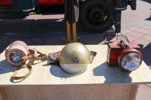equipo de bomberos antiguo, casco protector de bronce de fuego y linternas de minero sobre la mesa foto