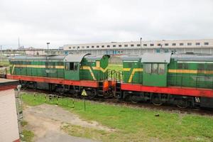 tren de carga con ruedas de hierro metálico verde, locomotora para el transporte de mercancías sobre raíles en la estación de tren foto