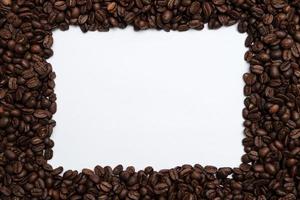 Roasted coffee beans surround a white frame. Copy space. Top view. photo