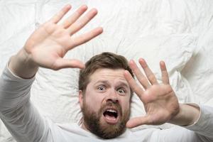 Man woke up from a nightmare, he makes a stop gesture, puts out his palms and looks frightened. Psychological health concept. Close-up. photo