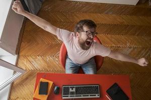 The man is tired and yawns while working with a computer at home, remotely. Modern lifestyle concept. photo