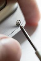 Close-up of a screw and a manual screwdriver about to unscrew it, on a white background. Macro photography. photo