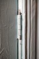 Metal hinge on a wooden painted door indoors, in a rural house. Country style. photo
