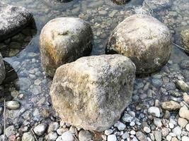 grandes y hermosos adoquines de piedras naturales redondas en agua, mar, lago, río. fondo, textura foto