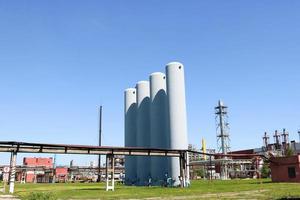 A large concrete technological industrial installation at a chemical petrochemical refinery with capacitive pipes by pumps compressors heat exchangers by pipelines and buildings photo