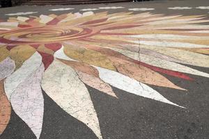 Texture pattern in the shape of a flower with petals of colorful beautiful on the road asphalt. The background photo