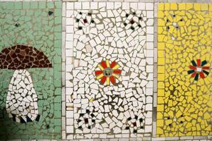 textura de un mosaico cerámico de fragmentos de vidrio de varios colores con un patrón de flores y un hongo. el fondo