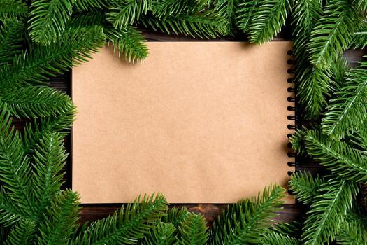 vista superior del cuaderno hecho de papel artesanal decorado con un marco hecho de abeto sobre fondo de madera. concepto de tiempo de año nuevo foto