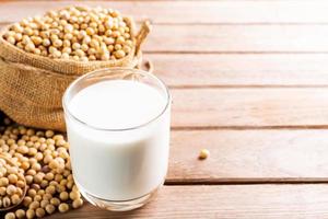 leche de soja en un vaso con soja en una mesa de madera desayuno orgánico, alto en proteínas, productos agrícolas saludables, vegetariano foto