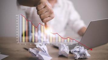 Depressed Businessman Leaning His Head Below a Bad Stock Market Chart photo