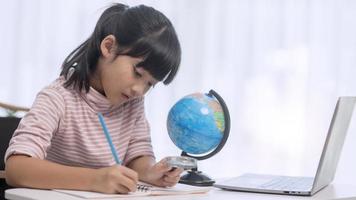 Asian little girl is learning the globe model, concept of save the world and learn through play activity for kid education at home. photo