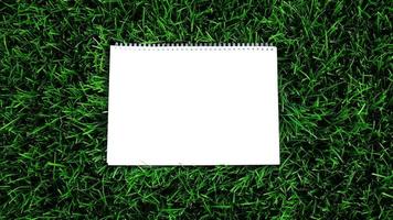 Empty white paper on green grass background. For message flat lay with copy space for text or products presentation. Nature concept, business and lifestyle environment. photo