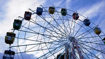 Colorful ferris wheels in the amusement park on a background of blue sky with clouds. Toned image. Bottom view photo