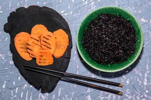 la comida saludable tiene arroz negro y vegetales en la mesa. foto