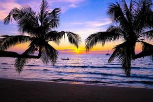 silueta de hermosa puesta de sol en la playa del mar con palmeras para viajar en tiempo de relajación de vacaciones, en el fondo de la naturaleza foto