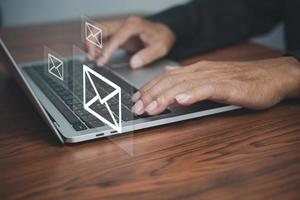 email marketing online working internet network concept. send e-mail or news letter. Businessman hands using Laptop typing on keyboard and surfing the internet on office with email icon. photo