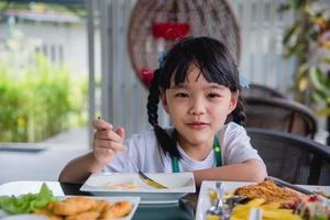 una joven asiática asiática come huevo frito en un plato en la mesa. foto