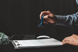 Man stamping approval of work finance banking or investment marketing documents on desk. photo