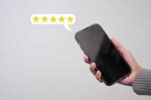 Female hand using a smartphone with a five-star pop-up icon for feedback, review, satisfaction service. photo